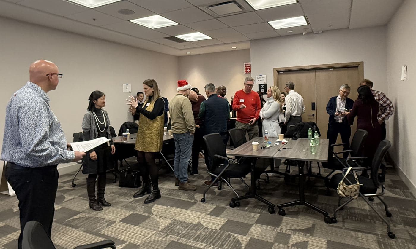 Colleagues mingle and talk in a meeting room during a DiSC workshop that opened a holiday celebration