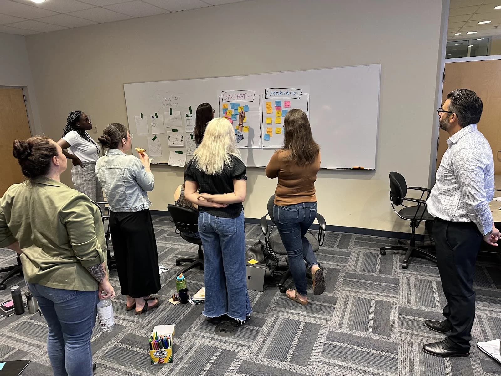 A university wellness team discussing its creature drawings and shared themes on the wall