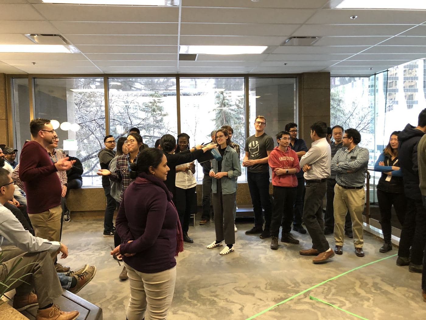 The whole group stands in a circle on the mezzanine while one group reports back