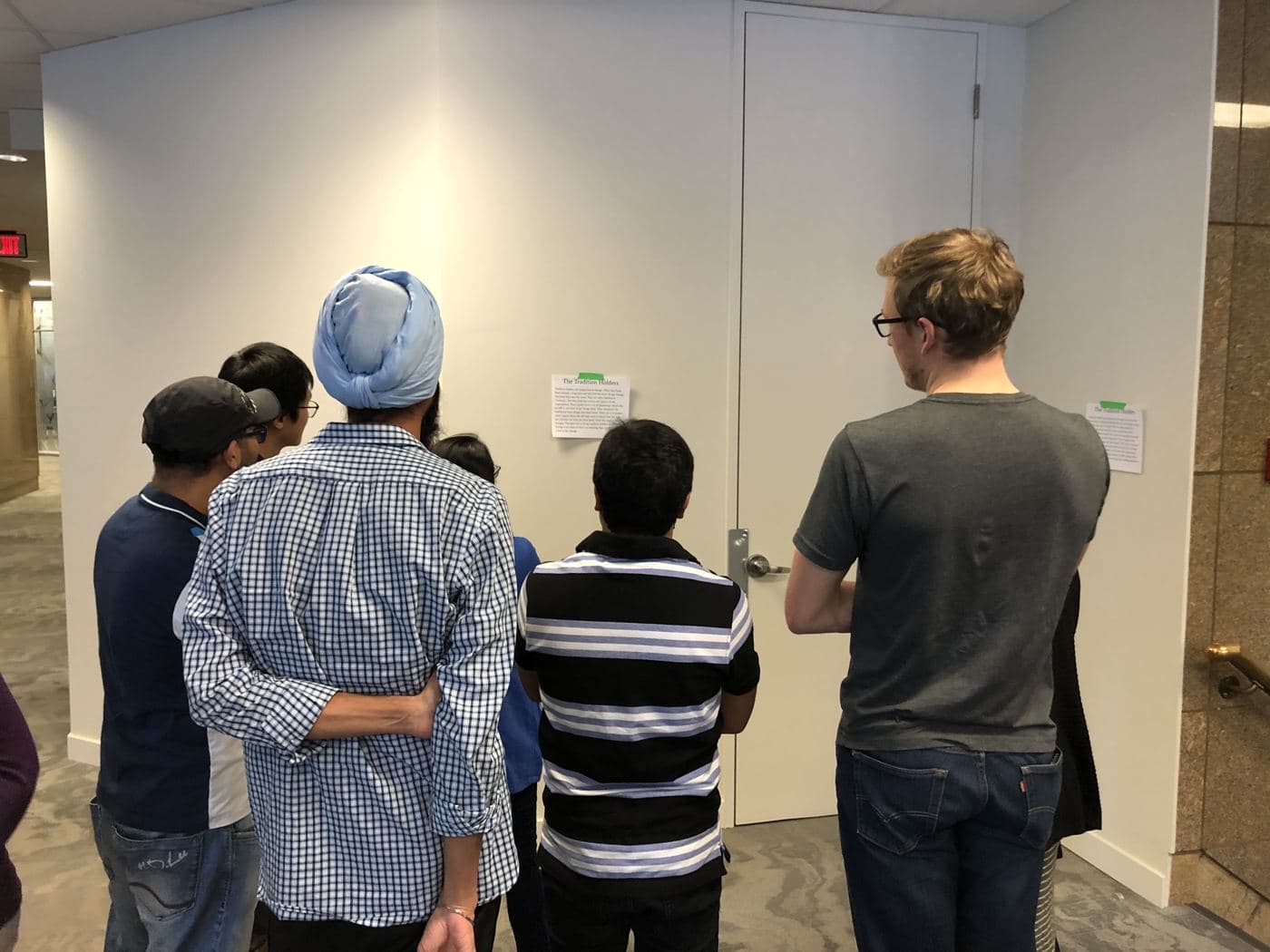 A small group stands together reading the description of its change style on the wall