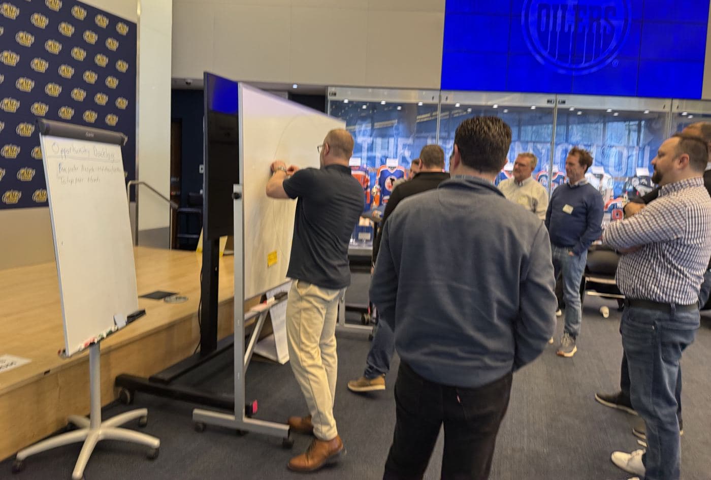 A participant places a sticky note on a whiteboard while colleagues watch