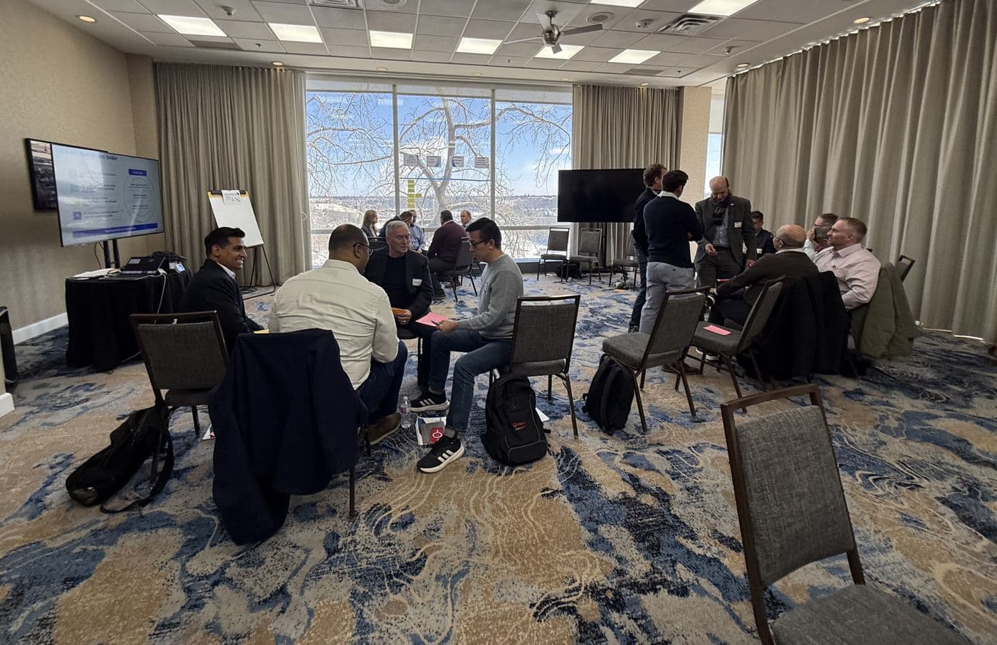 Leaders seated in small circles of chairs, deep in conversation in a bright workshop room